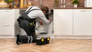 professional plumber repairing a garbage disposal under a kitchen sink